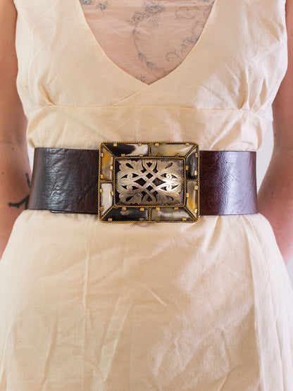 Close up of models waist wearing wide plain tan coloured  leather belt with a bone and metal  filigree belt.