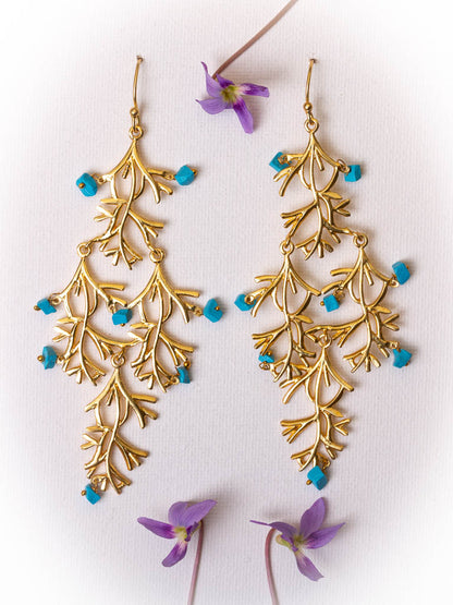 Turquoise and gold earring in the shape of a willow branch by Taboo Fashion Accessories.
