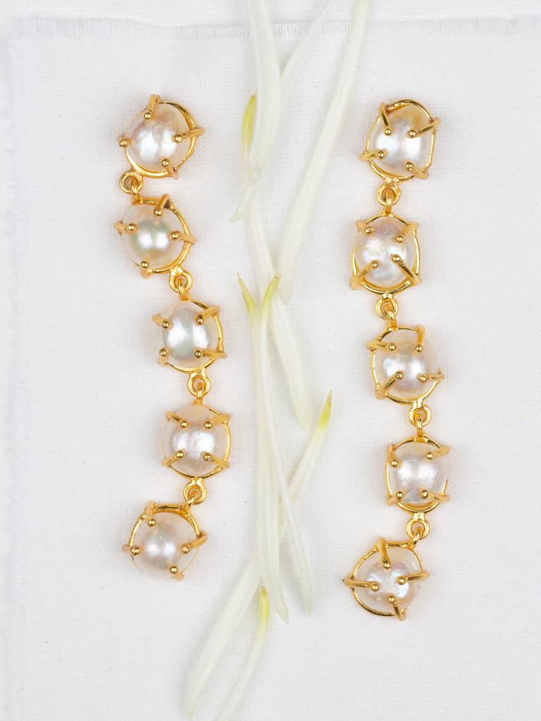 Pearl gold five drop earrings on an artistic display