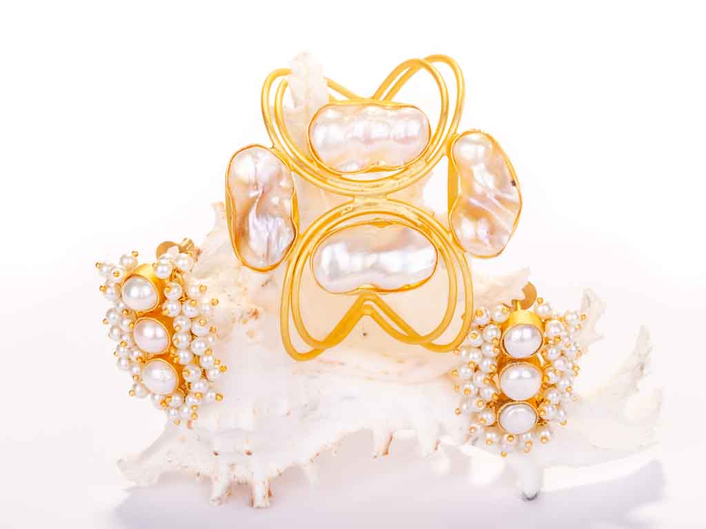 Earrings and pearl cuff sitting on a shell