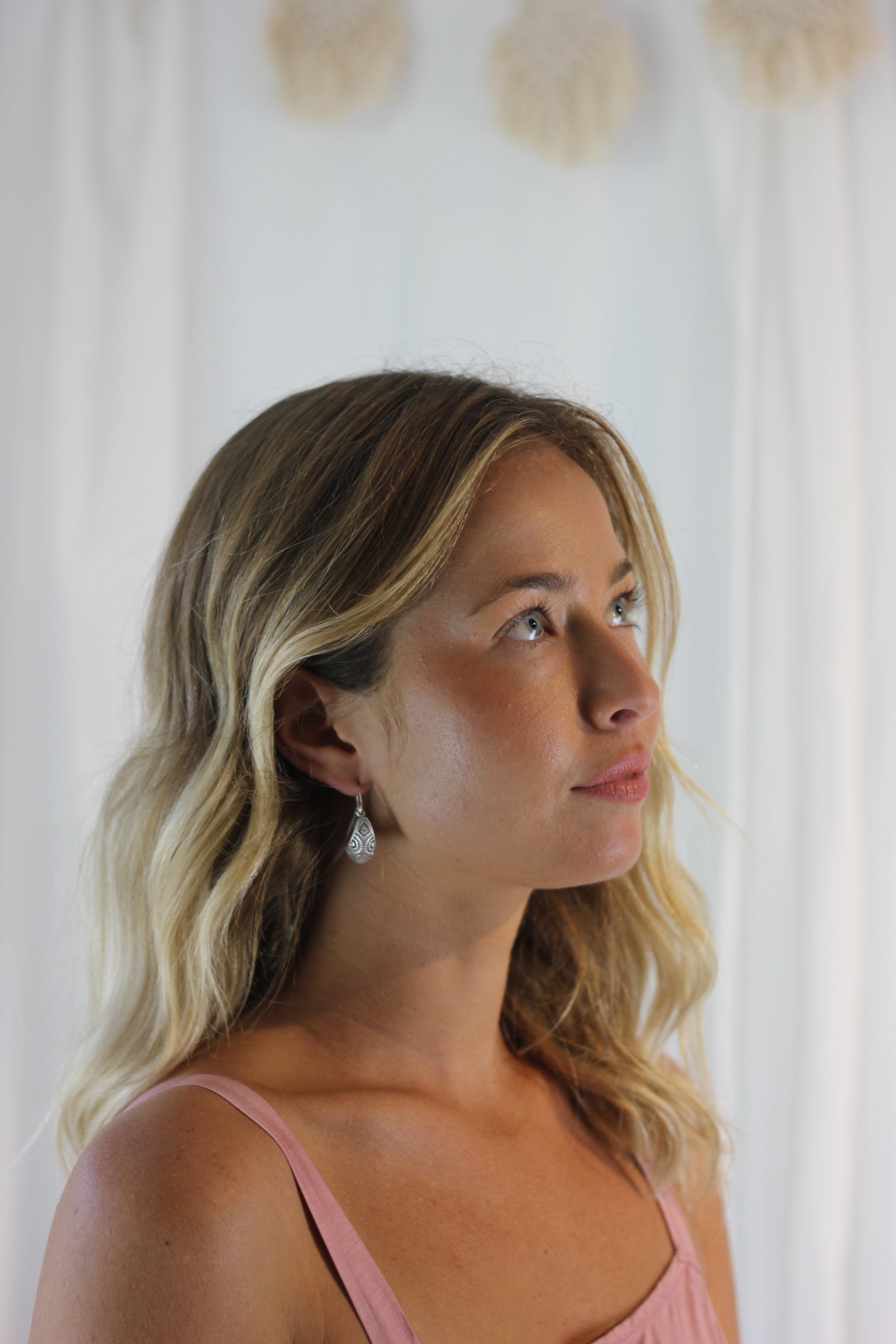 A woman wearing a pair of silver hammock shaped earring