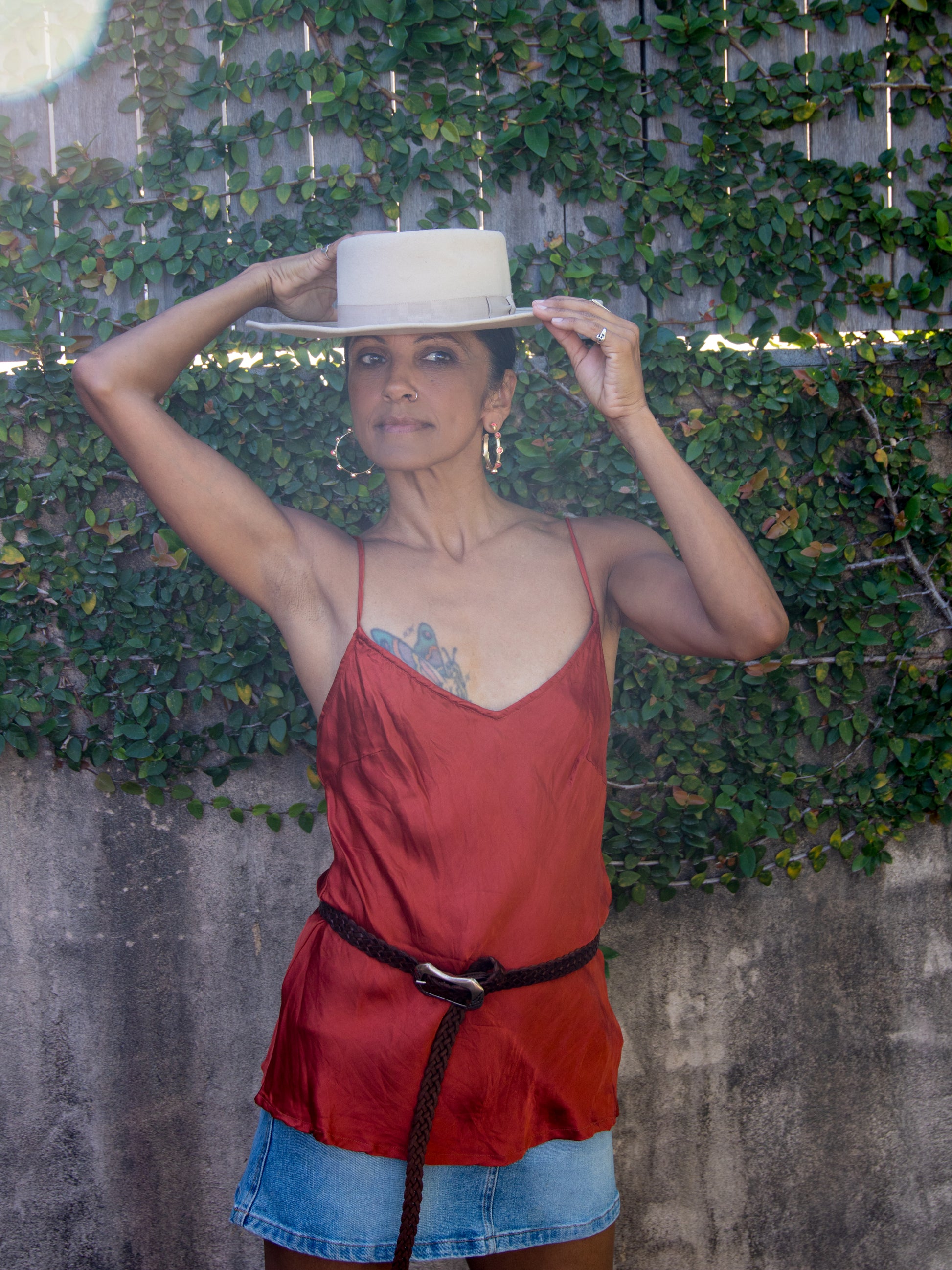 Woman wearing satin cami, hoop earrings and belt