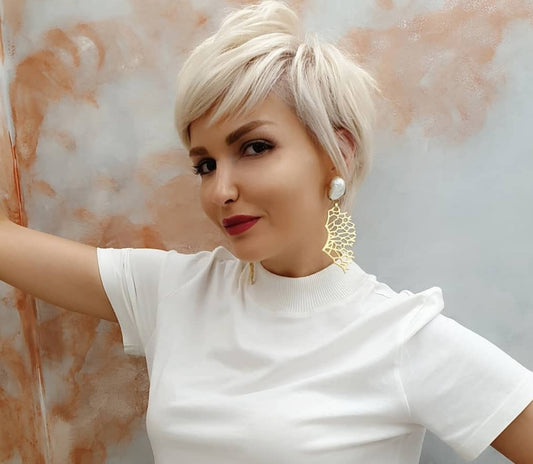 Woman wearing some large gold coral shaped earrings with pearl studs