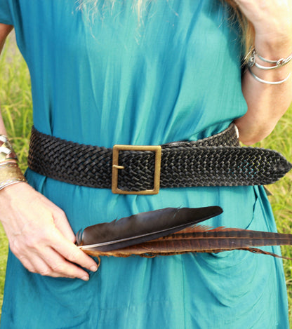 Woman wearing a wide leather black woven belt with brass buckle