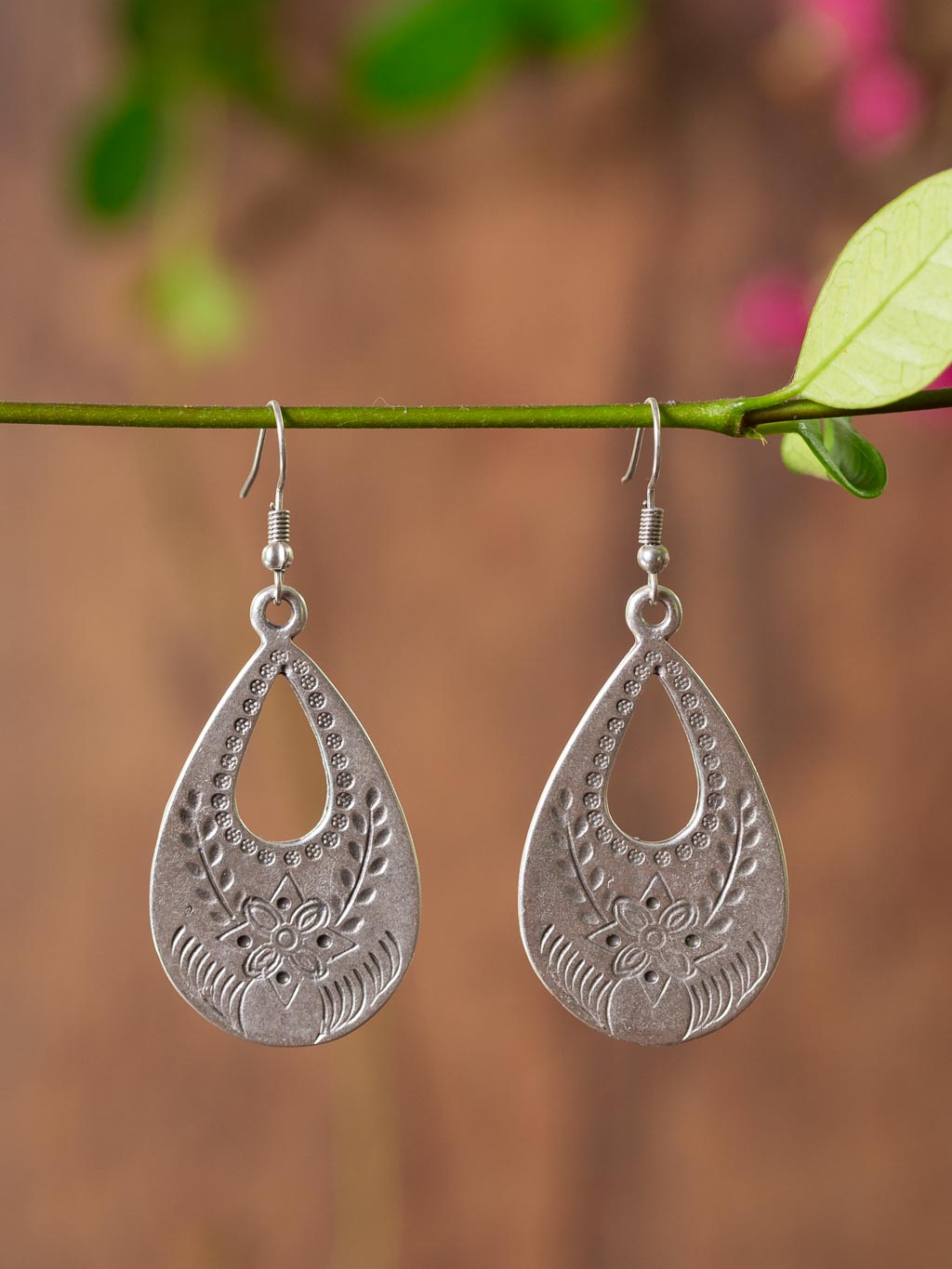 silver earring with a tear drop design and floral markings