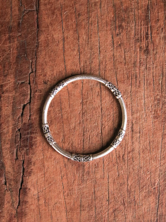 A silver bangle with scroll detailing