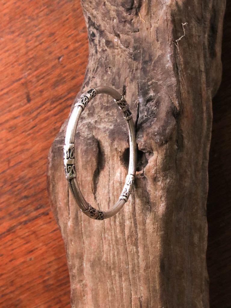 A silver bangle with scroll detailing