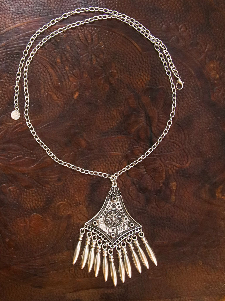 An Aztec style medallion with silver drops on a silver chain. Hook closure