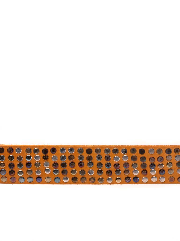 close up of leather belt covered in multi hued metal rivets 