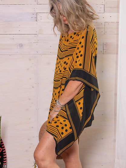A silk kaftan worn as a summer cover-up in mustard and black