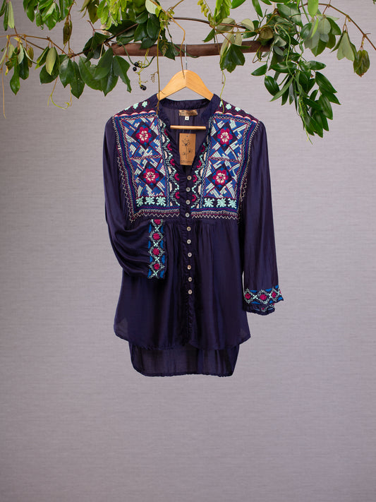 Long sleeve top hanging from vines, Embroidery in pinks and blues around cuffs and chest area, on a navy blue silk linen blended material.