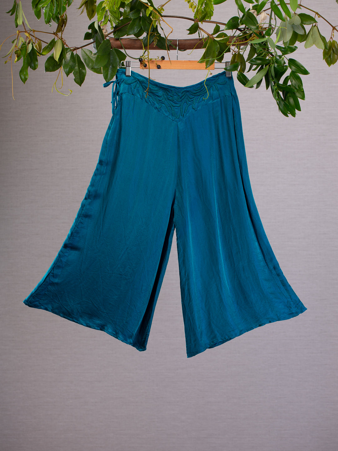 Refine your style with these Otomo silk pants, The silk material drapes in a complimentary way accentuated by the angled flare cut. The waist is tied and zipped at the sides and features a beautiful embroided design in the same colour as the material. 