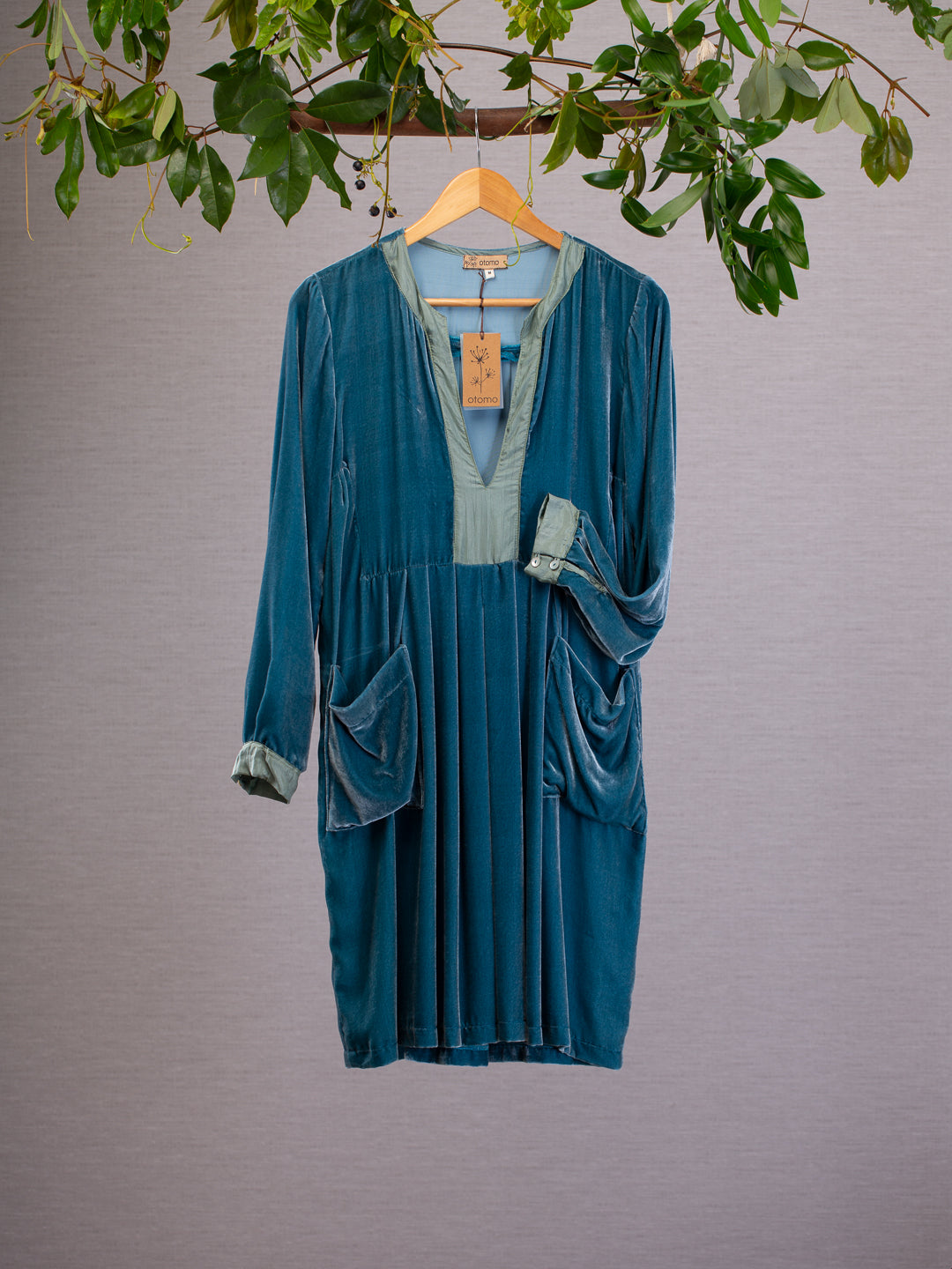 Teal Blue silk velvet dress hanging from vines, features generous pockets and shell buttons on the cuff.